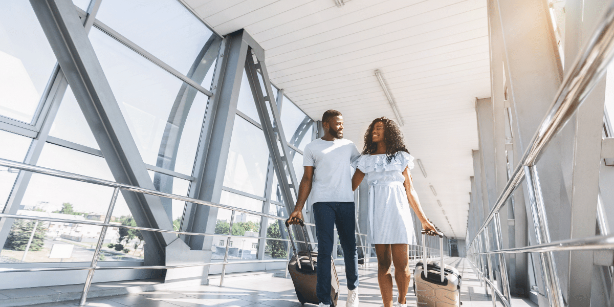 Couple with suitcases walking in airport terminal.