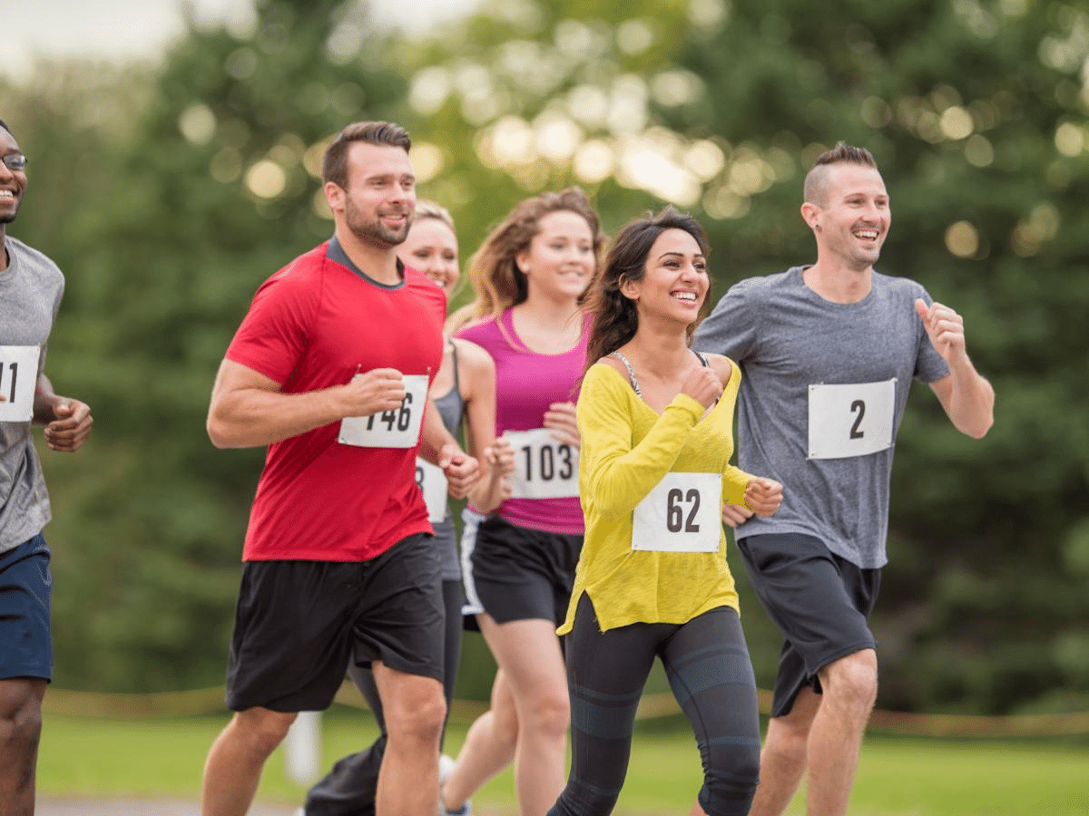 Performance & Recovery - Group of runners both male and female running with smiles on their face